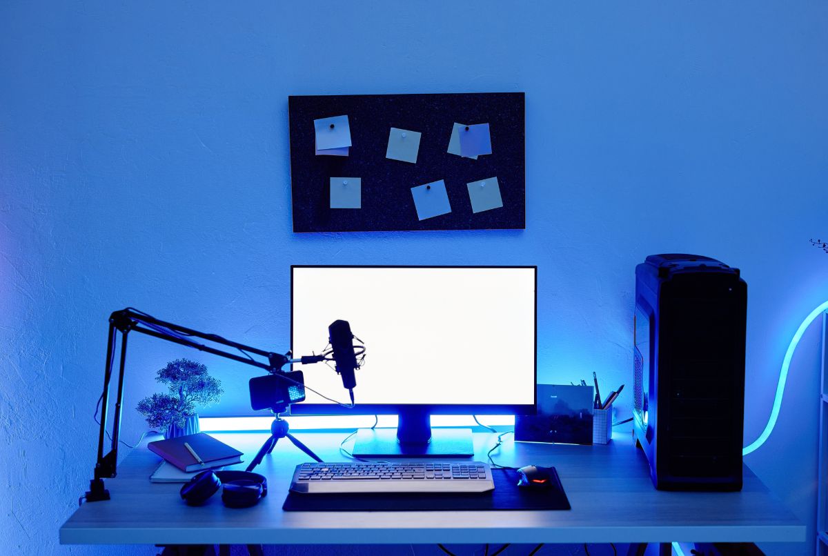 Setup PC gaming dengan monitor menampilkan rekaman gameplay, mikrofon kondensor, dan lampu ring biru