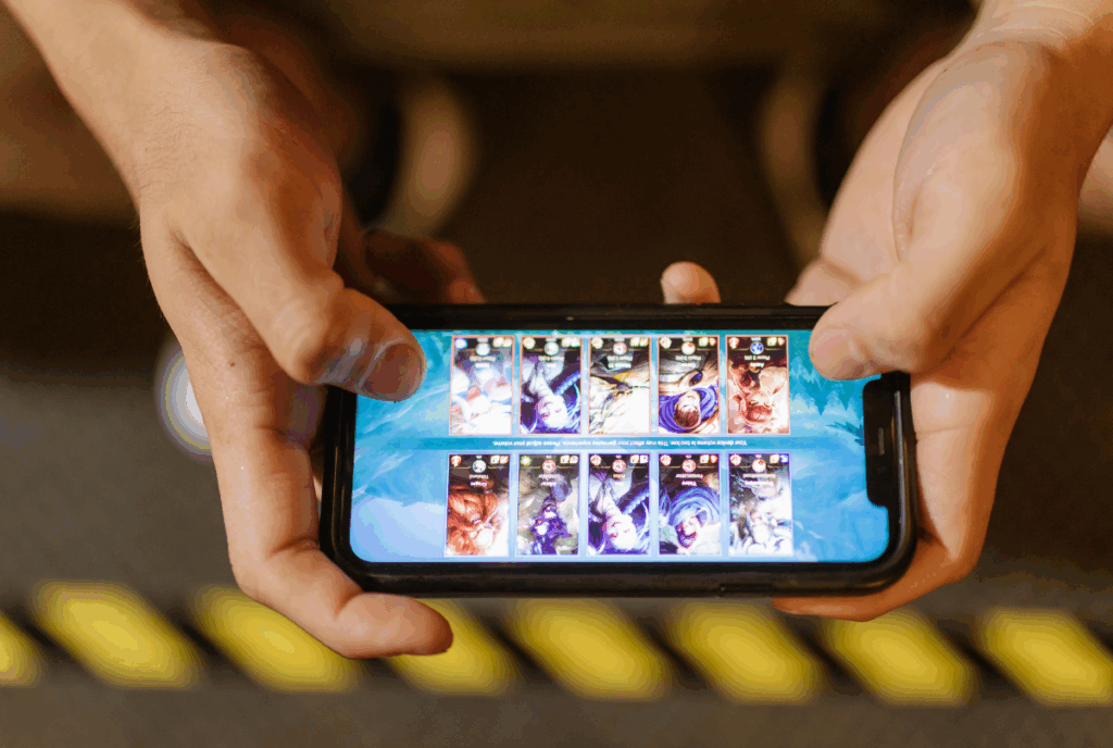 "Sepasang tangan memegang smartphone menampilkan layar game Mobile Legends Bang Bang, fokus pada tampilan kemenangan, merepresentasikan tips & trik game naik rank ML."