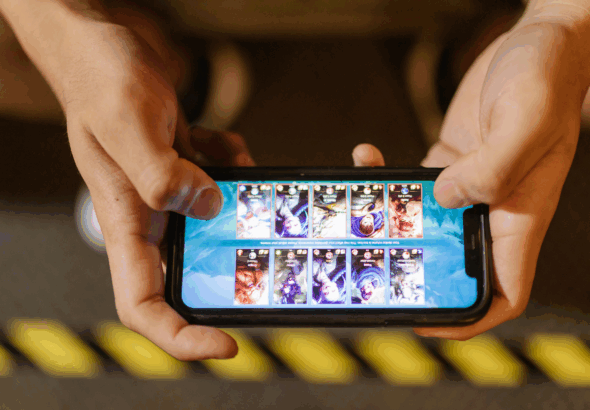 "Sepasang tangan memegang smartphone menampilkan layar game Mobile Legends Bang Bang, fokus pada tampilan kemenangan, merepresentasikan tips & trik game naik rank ML."